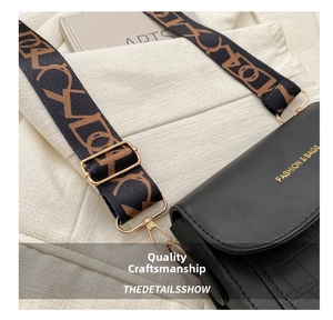 Detail of black stone pattern crossbody bag with gold text and jacquard fabric strap