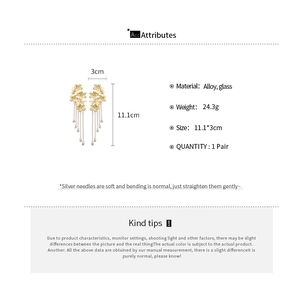 Detail view of gold flower earrings with long chain tassels and glass beads