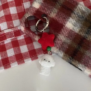 Cute plush dog keychain with red star and green bead on plaid background