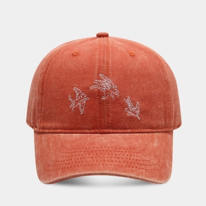 Détail de la broderie d'oiseau blanc sur la texture de la casquette en coton lavé