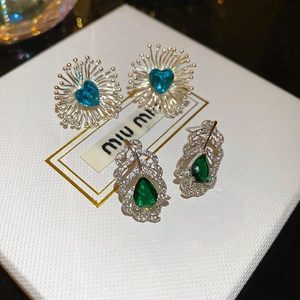 Vue détaillée de clous d'oreilles en zircon vert en forme de cœur et de poire sur cuir