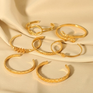 Polished 18K gold plated stainless steel knot bracelets on elegant beige silk background