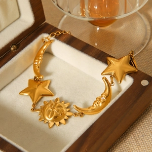 Detail of 18K gold celestial sun moon star charms resting in a luxury wood jewelry box