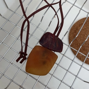 Detail of bohemian geometric resin pendant with deep red and amber marble texture