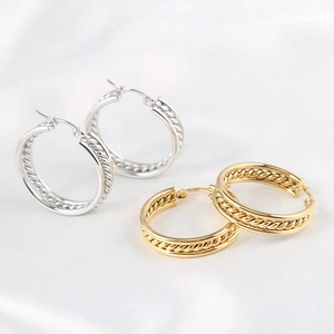 Minimalist triple-hoop earrings in gold and silver finish on elegant white silk background