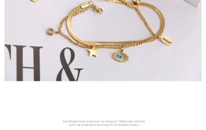 Detail of gold evil eye and star charms on a layered stainless steel chain necklace