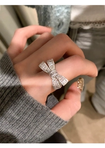 Close-up of bow ring with cubic zirconia on a hand wearing a grey knit sweater