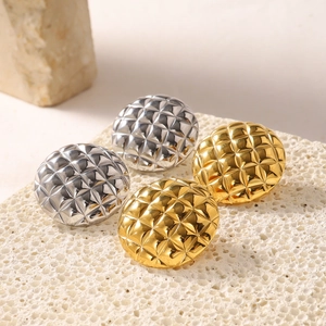 Detailed close-up of gold and silver sphere stud earrings with a diamond lattice texture