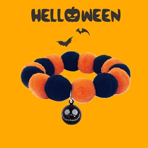 Halloween pet collar featuring orange and black plush balls with a skull bell charm