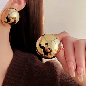 Minimalist large golden sphere earrings with high-polish mirror finish on model