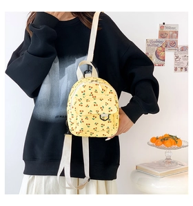 Detail of yellow corduroy mini backpack featuring cherry prints and front pocket
