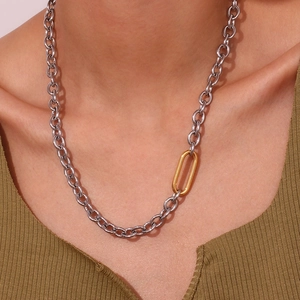Detail of silver link chain necklace with gold oval accent worn on olive green top