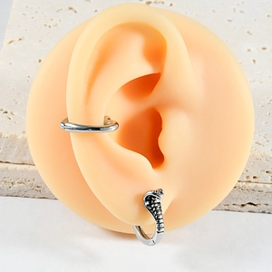 Detail of silver stainless steel hoop earrings with snake head motif on silicone ear model