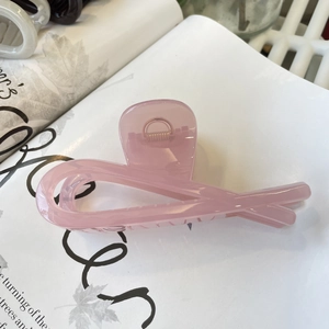 Pink translucent ribbon shark hair clip placed on a book for a minimalist aesthetic