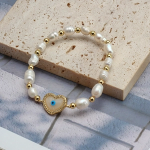 Detailed close-up of heart-shaped evil eye pendant on freshwater pearl bracelet