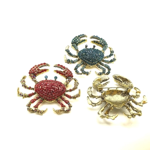 Detailed front and back views of crystal crab brooches in red, blue and gold alloy