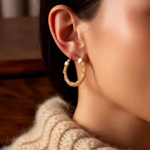 24k gold-plated hoop earrings with intricate braided metal texture worn by a model