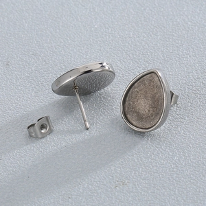 Polished silver stainless steel teardrop earring studs and backs on gray background