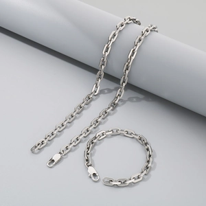Silver paperclip link chain necklace and bracelet set displayed on a grey pedestal