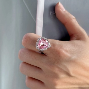 Close-up of pink heart-shaped crystal ring with micro-pave setting on a silver band