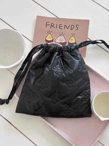 Detail of black drawstring storage bag with embossed bow patterns and shiny finish