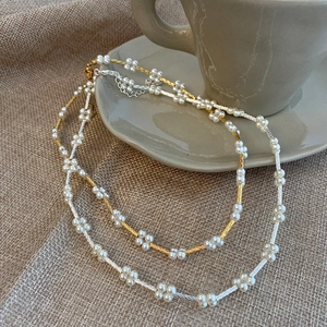 Macro detail of elegant double-layered pearl flower necklaces on a textured background