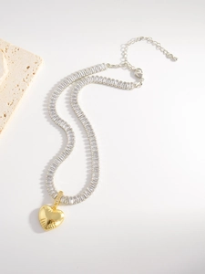 Close-up of heart pendant necklace with baguette-cut zircons and golden metal finish
