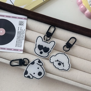 Detail of cartoon dog acrylic keychains including Bichon and Bulldog on a fabric tray