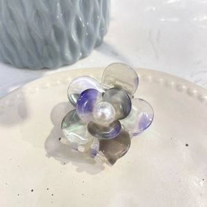 Macro shot of acetate flower hair claw clip with purple petals and a central pearl detail