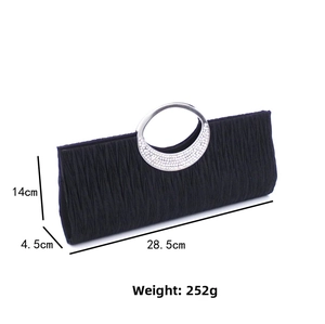 Macro detail of black pleated fabric evening bag with rhinestone-set metal handle