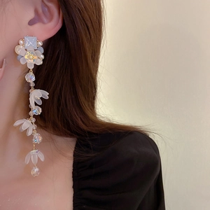 Detail showing long floral tassel earring with crystals and white petals on a model