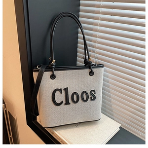 Detail of canvas tote bag with black leather trim and Cloos lettering by the window