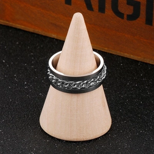 Close-up of a stainless steel spinner ring with a black chain inlay on a wooden stand