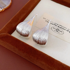 Macro detail of silver drop earrings with vertical striped texture on vintage card