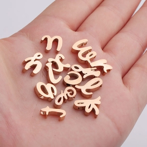 Macro view of rose gold stainless steel alphabet letter beads for DIY jewelry in a palm