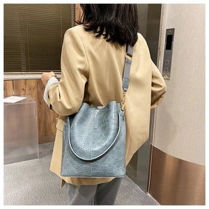 Detail view of blue crocodile pattern bucket bag with wide grey shoulder strap