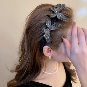 Macro detail of butterfly hair clip with grey rhinestones and elegant fabric feathers