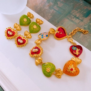 Detailed close-up of vintage heart earrings and bracelet with colorful enamel and pearls