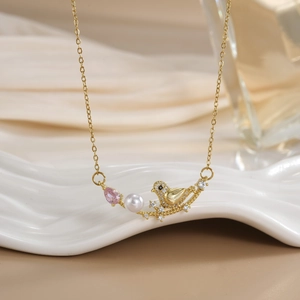 Detail of bird pendant necklace with pearl and pink zircon on a ceramic tray