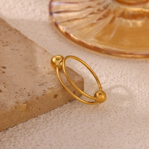 Macro shot of gold double-layer open ring with beads on a beige textured stone base
