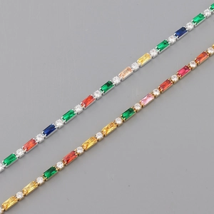 Gros plan de chaînes plaquées or et argent avec cristaux de zircon colorés sur fond gris