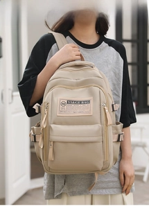 Detailed view of beige multi-pocket school backpack with side straps and brand patch