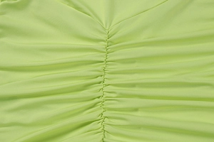 Detailed view of the elegant fruit green ruched fabric and gathered texture on the dress
