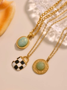 Detail of gold chain necklaces with green natural stone and checkered enamel pendants