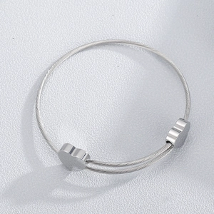 Detailed close-up of silver stainless steel wire cuff bracelet with dual heart charms