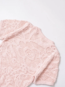 Gros plan du haut en maille duveteuse rose clair montrant la texture douce ajourée