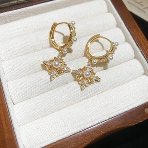 Macro shot of 18K gold plated rhombic earrings with pearls and zircon in a jewelry box