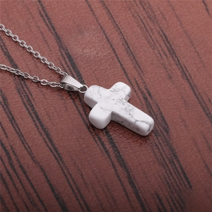 Macro detail of minimalist stainless steel cross necklace with white marble stone texture