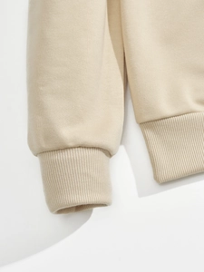 Detailed close-up of beige sweatshirt ribbed cuffs and hem with high-quality stitching