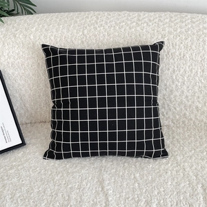 Detailed view of square black and white checkered cushion cover on a soft white sofa